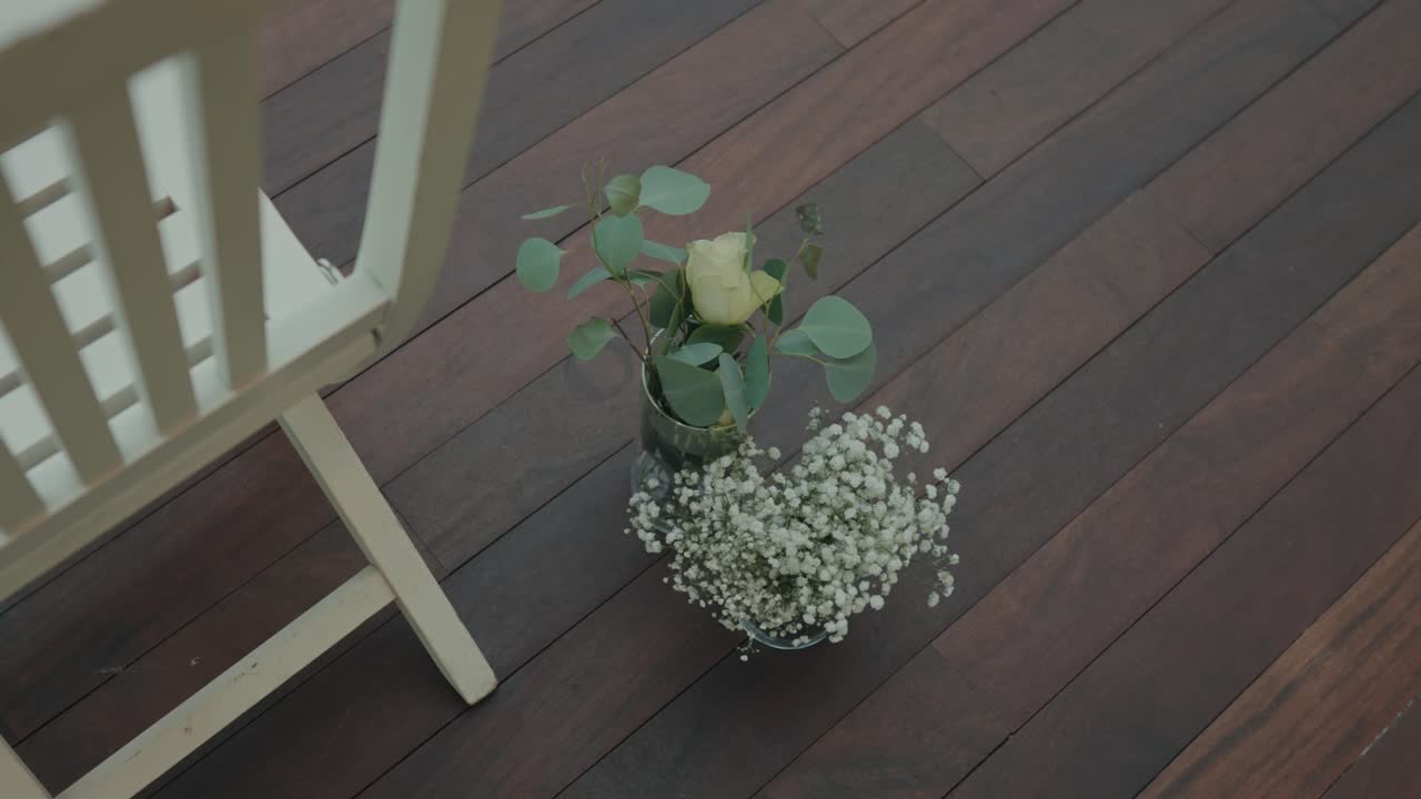 To glasvaser med rose og eukalyptus på indendørs trægulv.