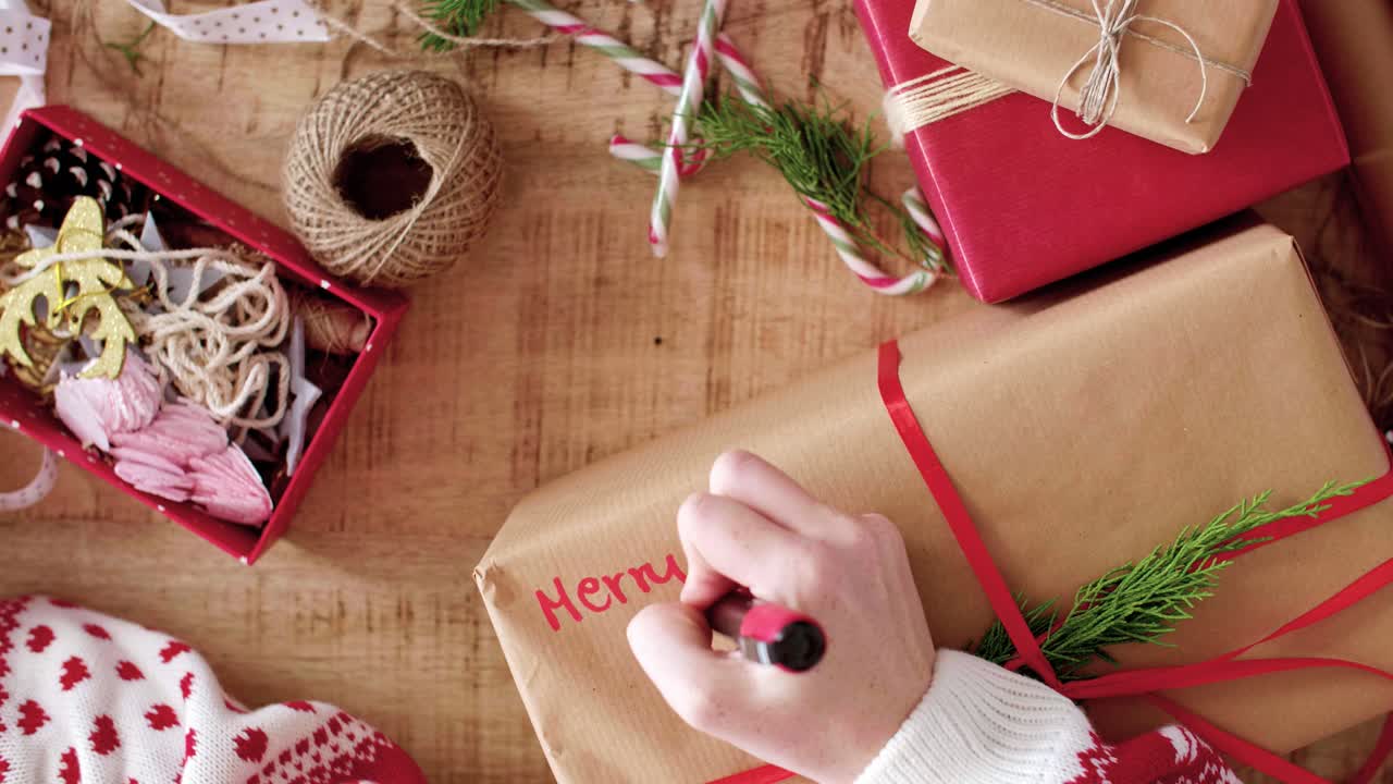 Woman writing ''Merry Christmas'' on the christmas present