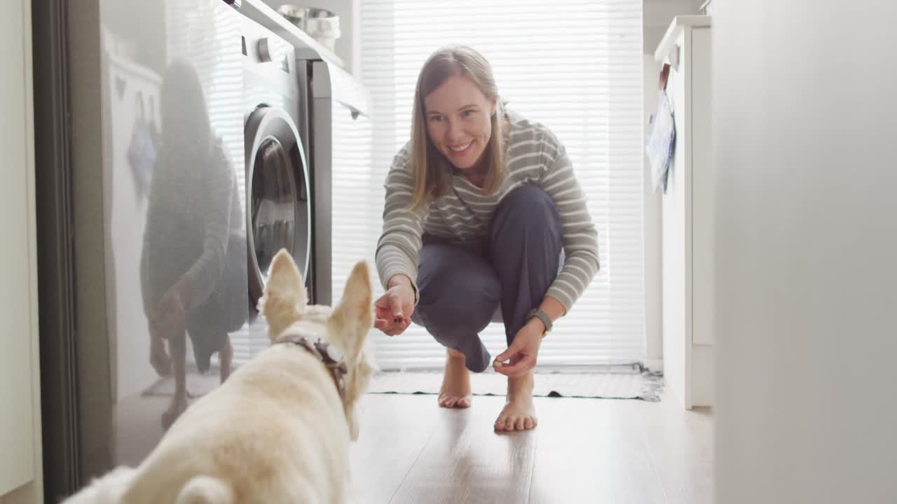 mujer caucásica alimentando a su perro en la cocina en casa