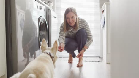 Caucasian-woman-feeding-her-dog-in-the-kitchen-at-home