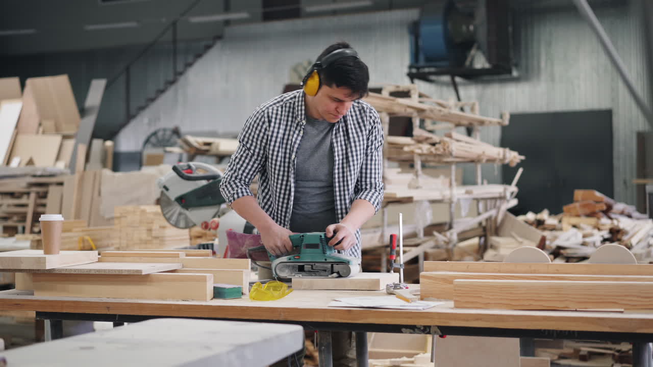Woodworker using a band sander in a workshop