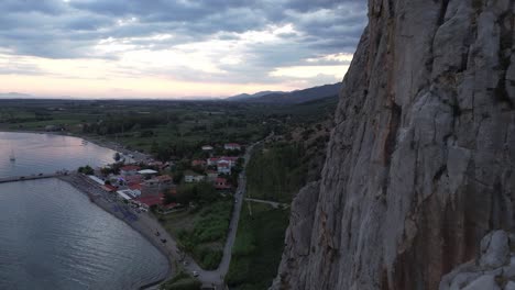 Idyllic-rural-village,-red-rooftop-houses-as-harbor,-seen-from-above-in-flyover-drone-shot-along-steep-rocky-cliff