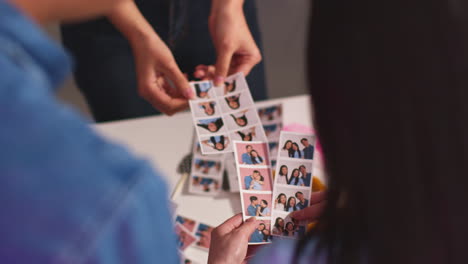 close up of a group of friends having fun looking at prints from photo booth with props 14