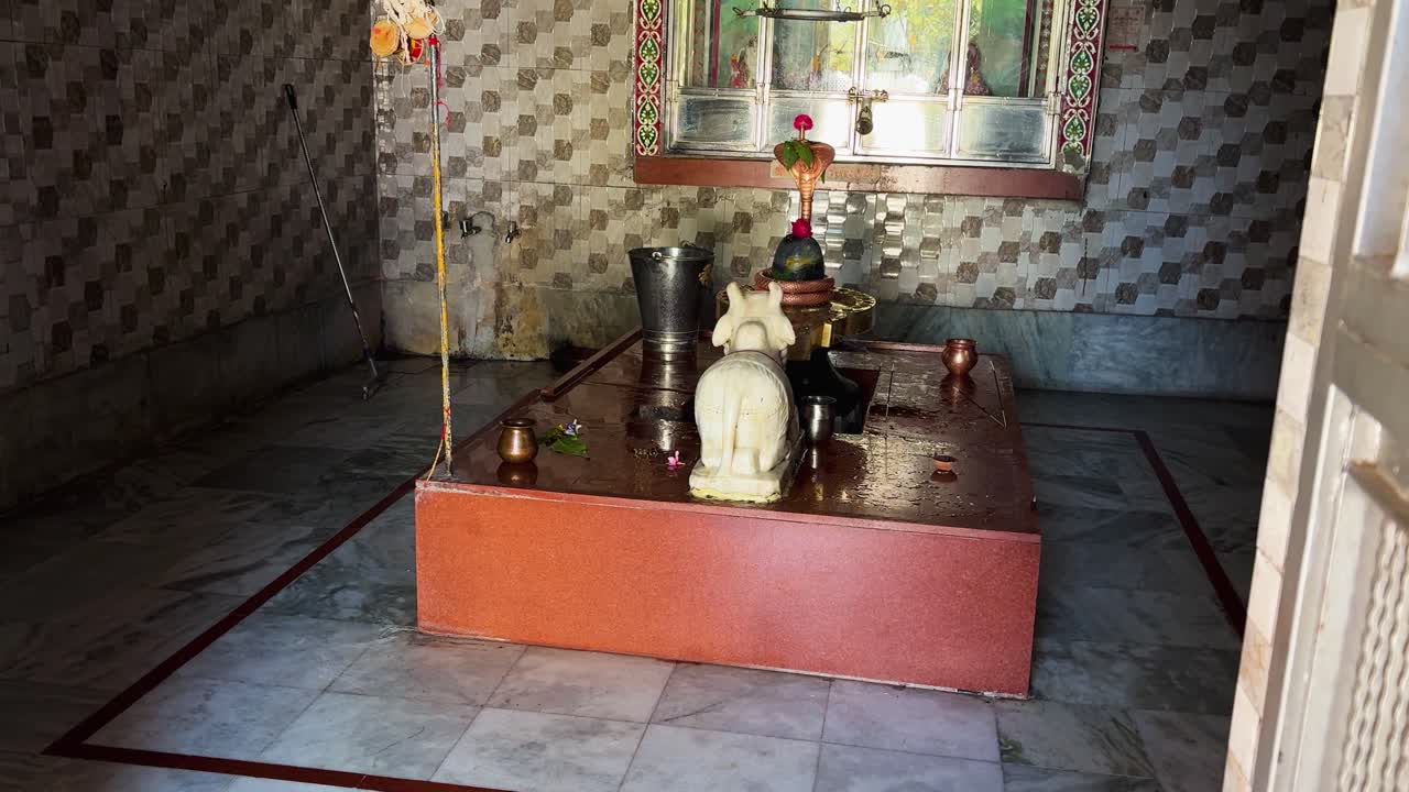 Scena di culto religioso indiano con lingam sacro e interno del tempio