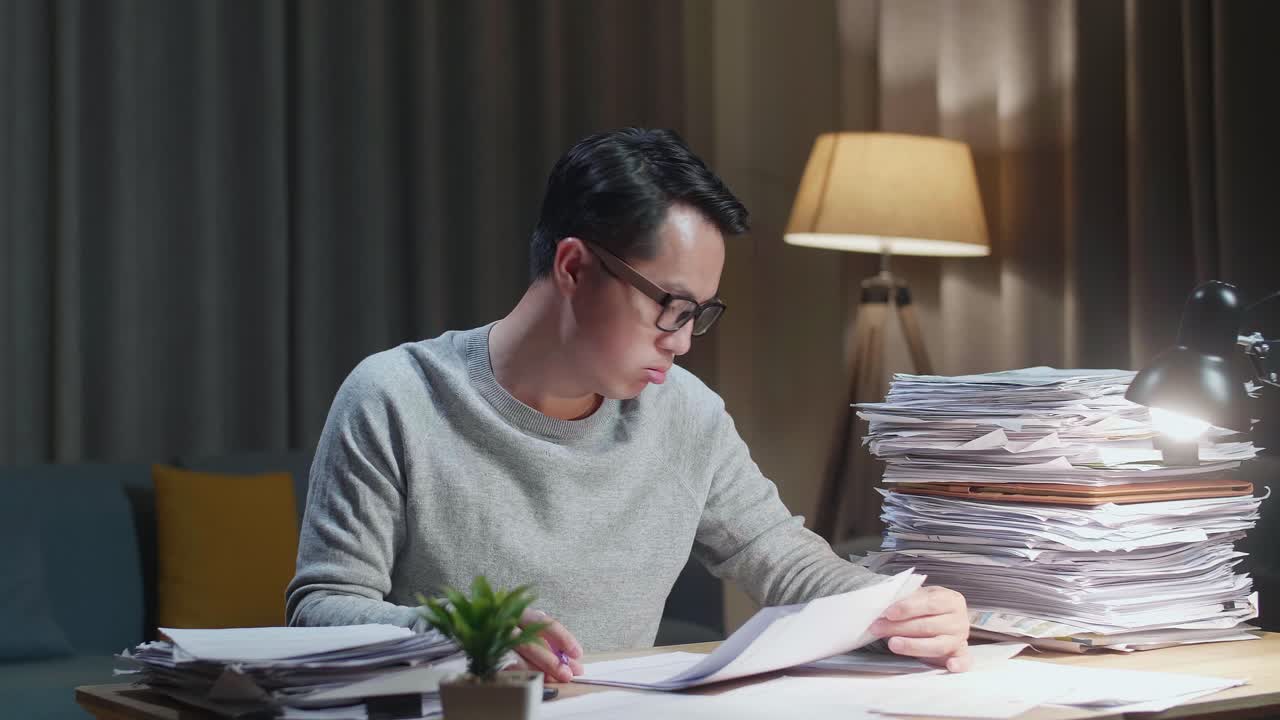 Tired Asian Man Shaking His Head While Working Hard With Documents At Home