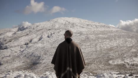 unrecognizable traveler contemplating snowy ridge in sunlight