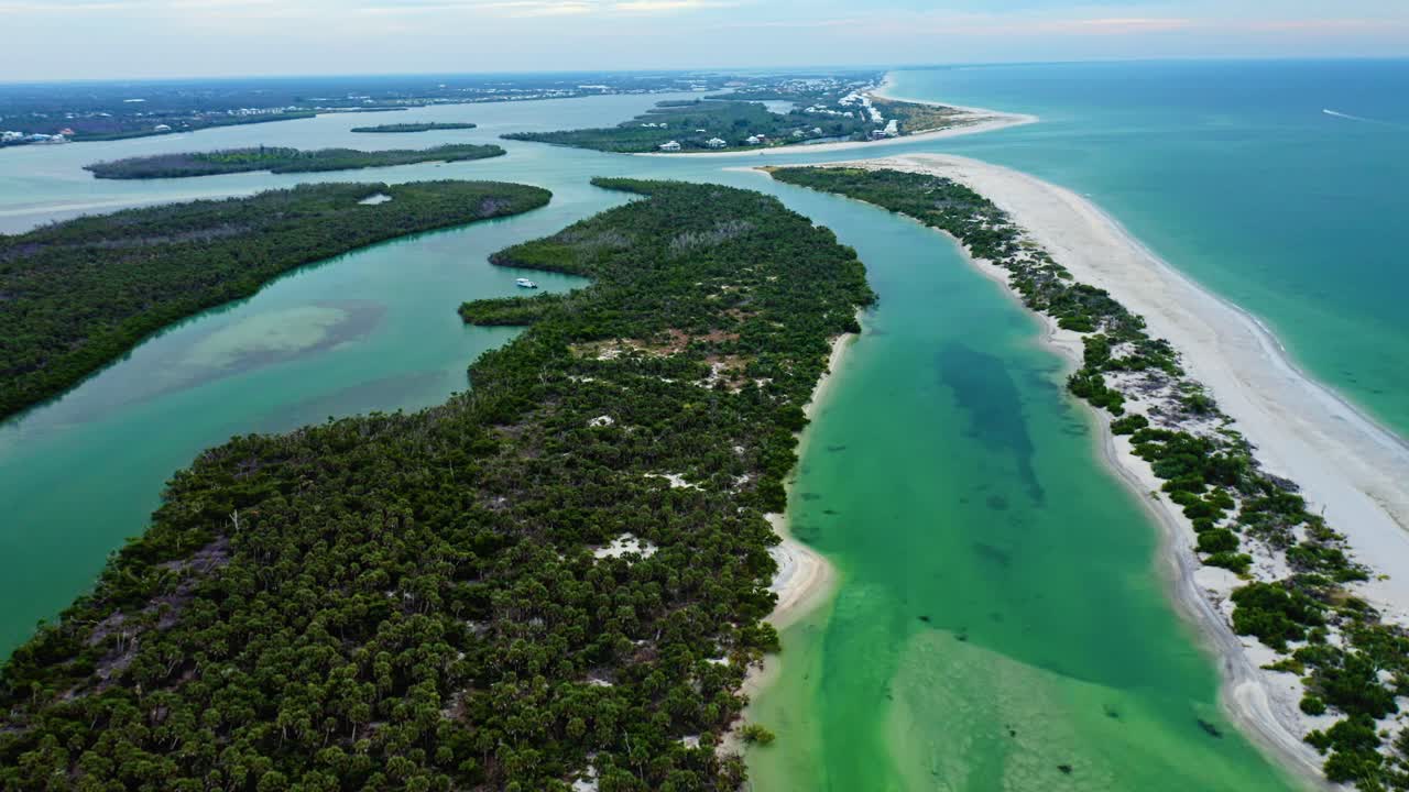 Mangrove islands and bright sandy shoreline shape the winding green waterways leading toward Stump Pass, where clear Gulf shallows meet the long barrier stretch of Manasota Key on Florida’s Gulf Coast