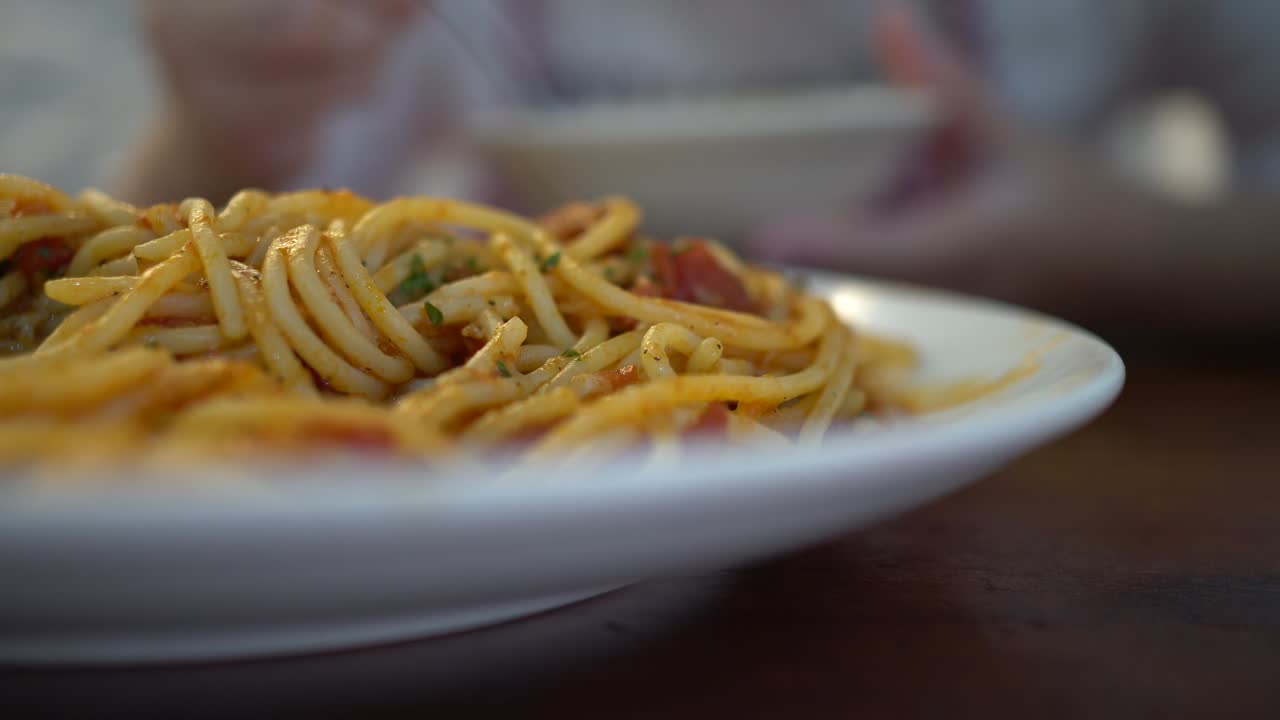 una niña pequeña come espagueti de mariscos de tomate en un restaurante. el enfoque está en el frente.