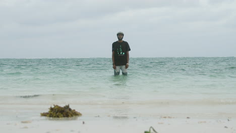 slow motion shot of a handsome young black man in the ocean water looking at the camera