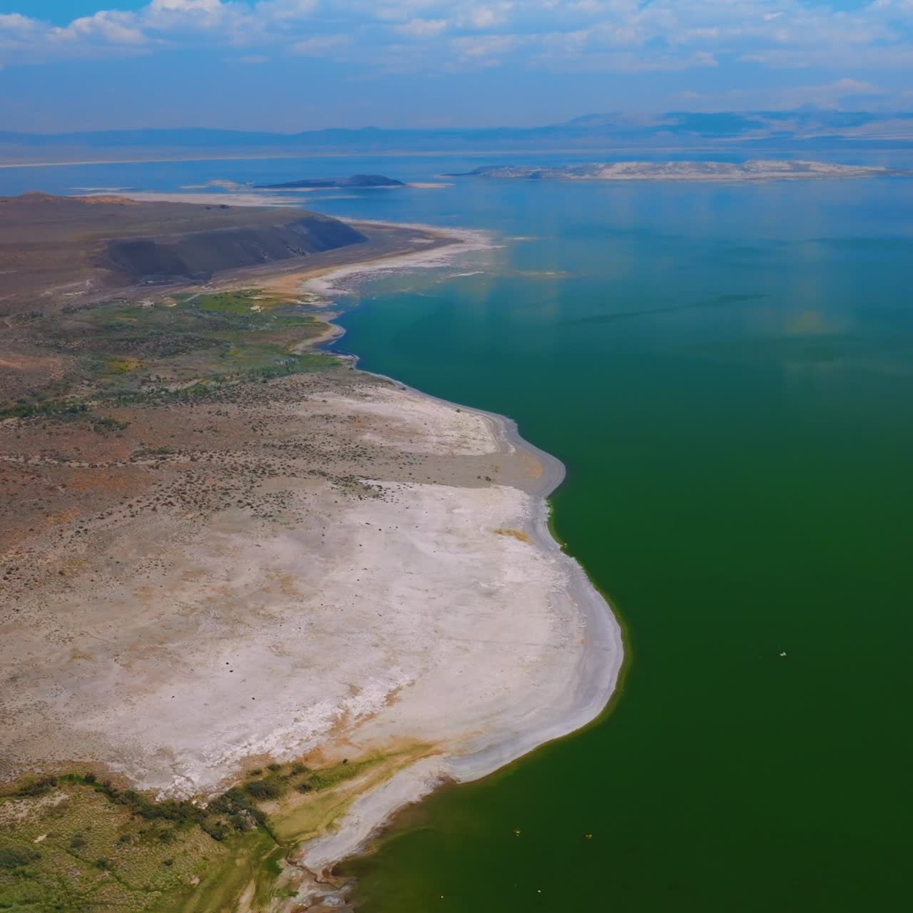 Flying over the bordering line between water and land. Bare with no vegetation shore of beautiful salty Mono Lake on sunny daytime. Top view