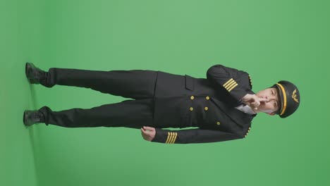 아시아 남성 조종사가 카메라를 바라보고 녹색 스크린 배경 스튜디오에서 shh 제스처를합니다.
