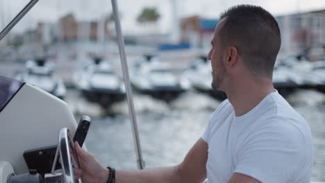 smiling man driving a boat at a marina