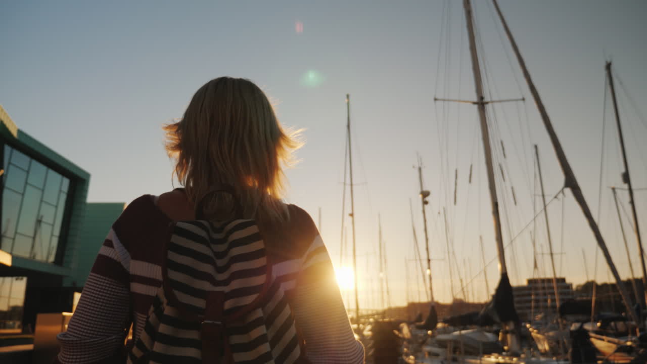 молодая женщина прогуливается по престижному району бергена возле пирса с яхтами.