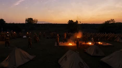 soldiers camped out around a bonfire at sunset