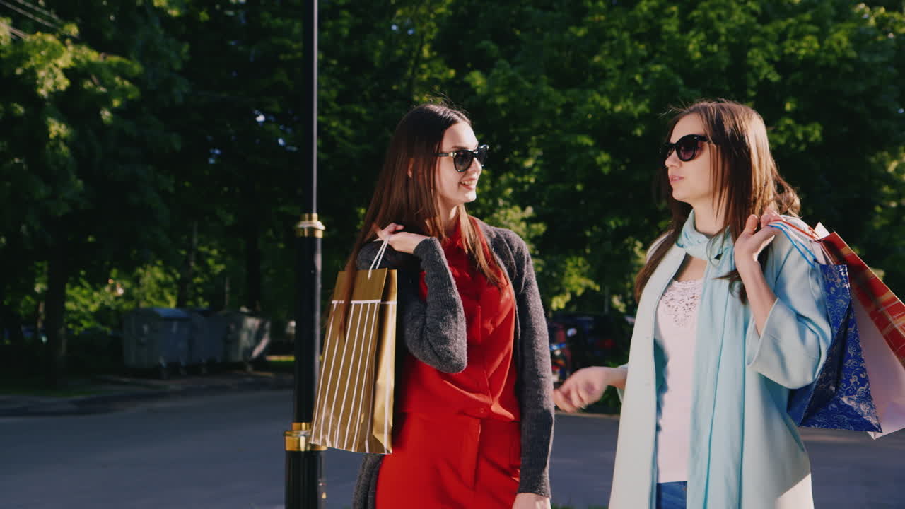 steadicam disparó a dos mujeres jóvenes con bolsas de compras hablando en la calle sonriendo