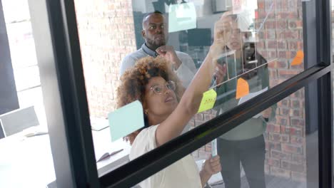 Diverse-male-and-female-colleagues-in-discussion,-brainstorming-at-glass-wall-in-office,-slow-motion