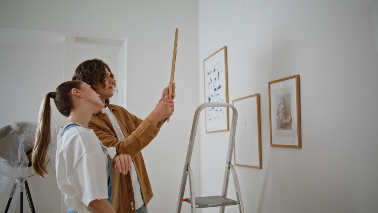 Family discussing home decoration holding framed artwork in light living room