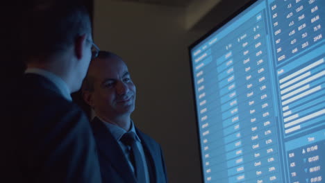 cheerful businessmen analyzing big data on big digital screen with teammate