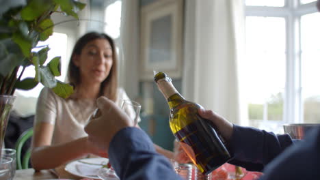 hombre abriendo una botella de champán en la comida del día de san valentín