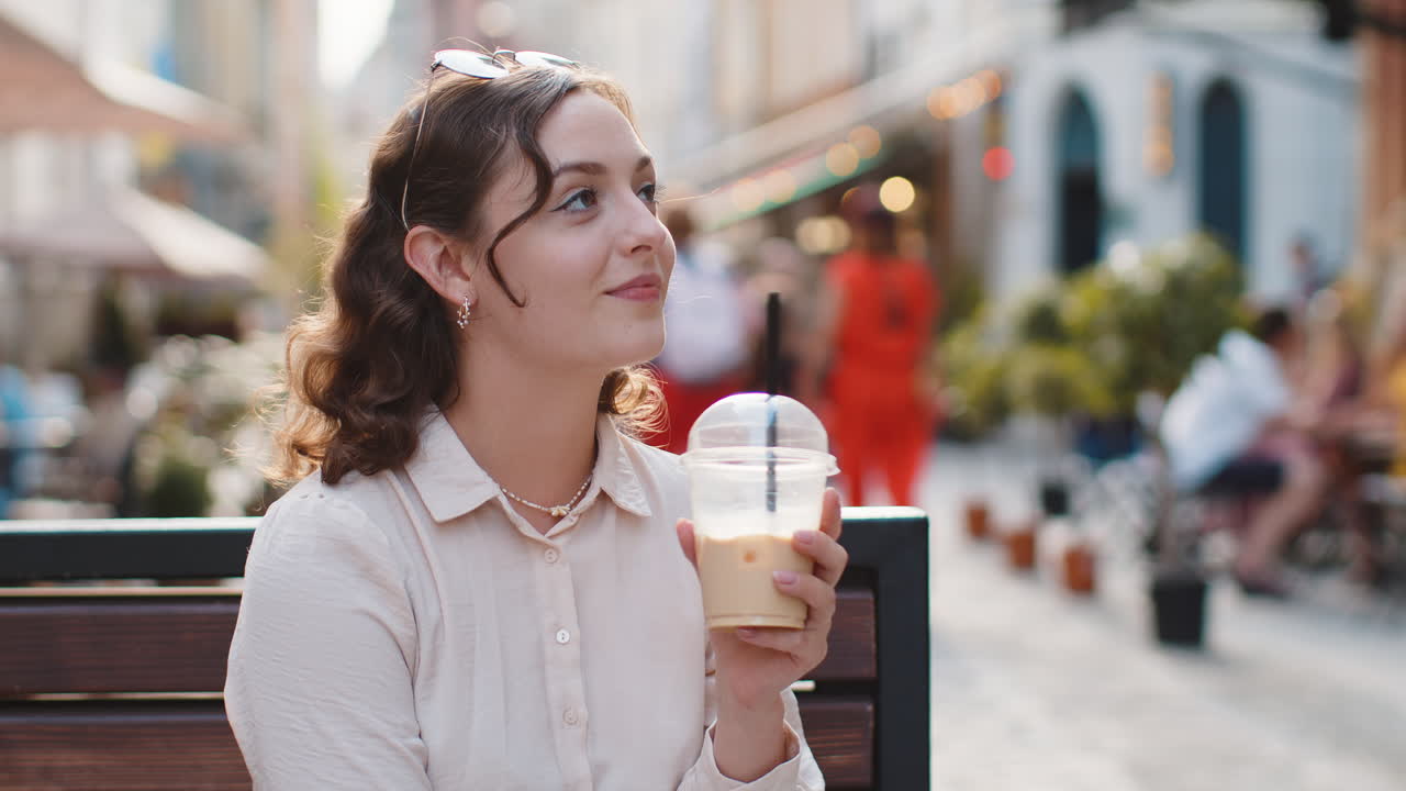 Woman enjoying drinking morning cold coffee drink with ice relaxing taking a break in city street