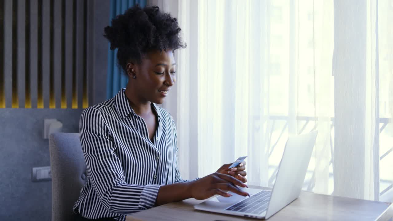 imagen amplia de una joven negra ocupada sosteniendo su tarjeta de crédito