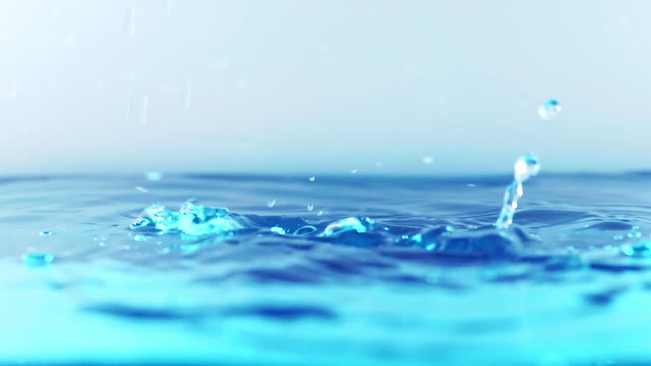 슬로우 모션의 깨끗한 물 표면은 물이 튀는 상점으로 화면을 채우고 기포로 액체 표면을 흔들고 있습니다.