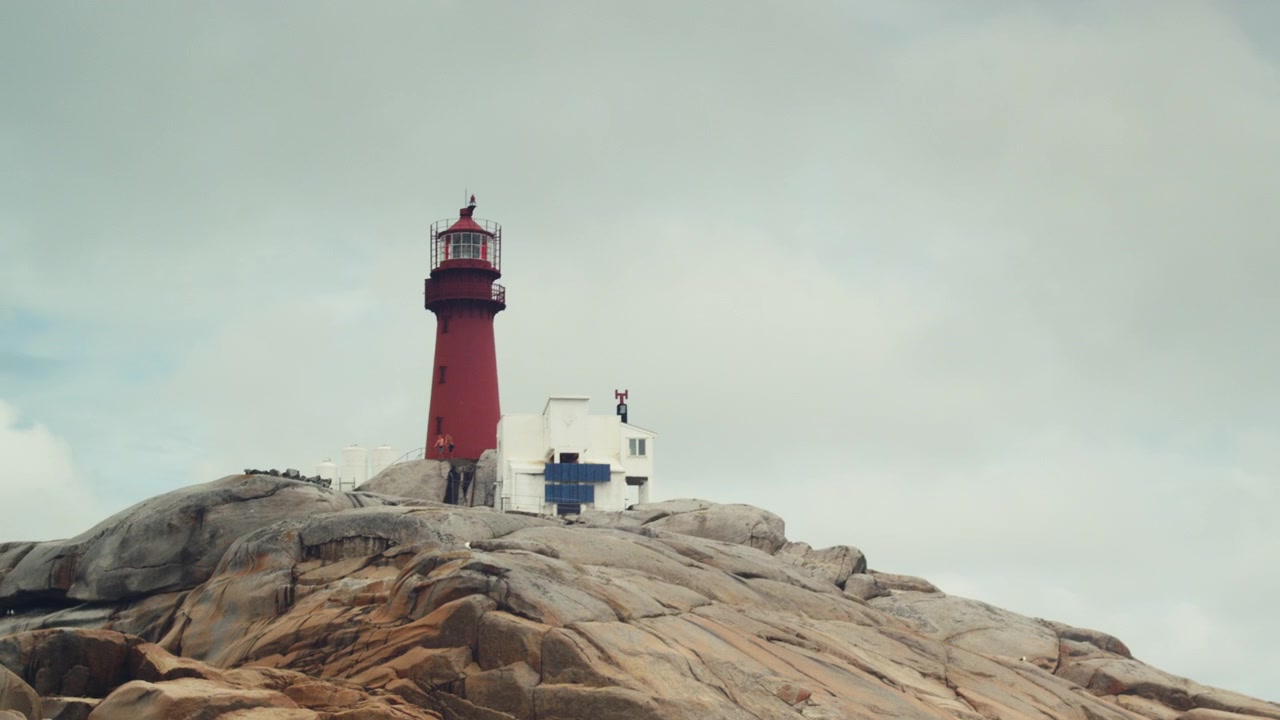Filmischer Leuchtturm, vom Meer aus gesehen. Möwen fliegen herum. Kamera wackelt synchron mit den Wellen.