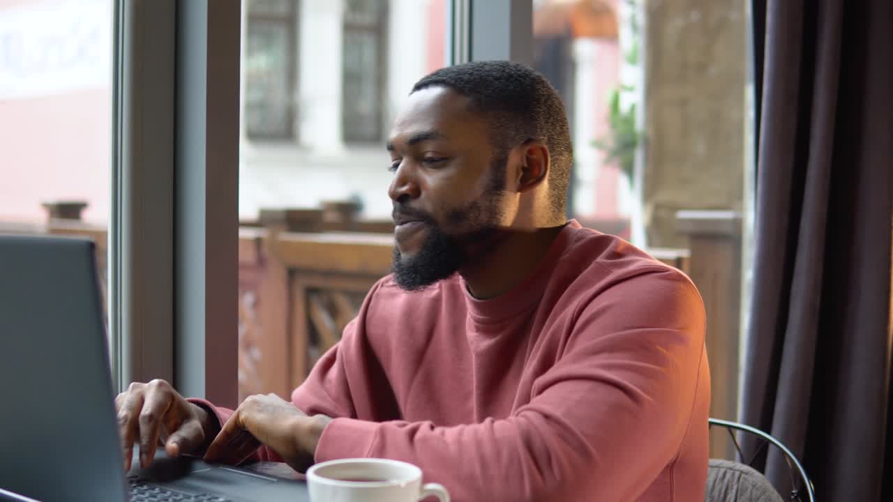 African american young man communicating by conference call speak looking at computer in cafe