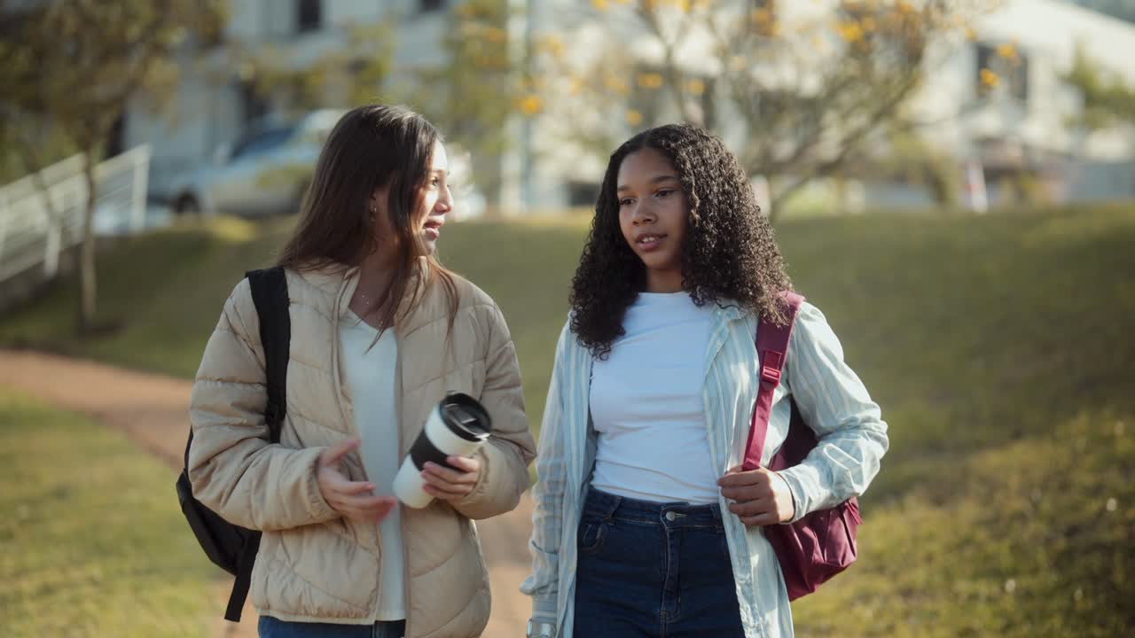 Two young female students walking and talking on university campus
