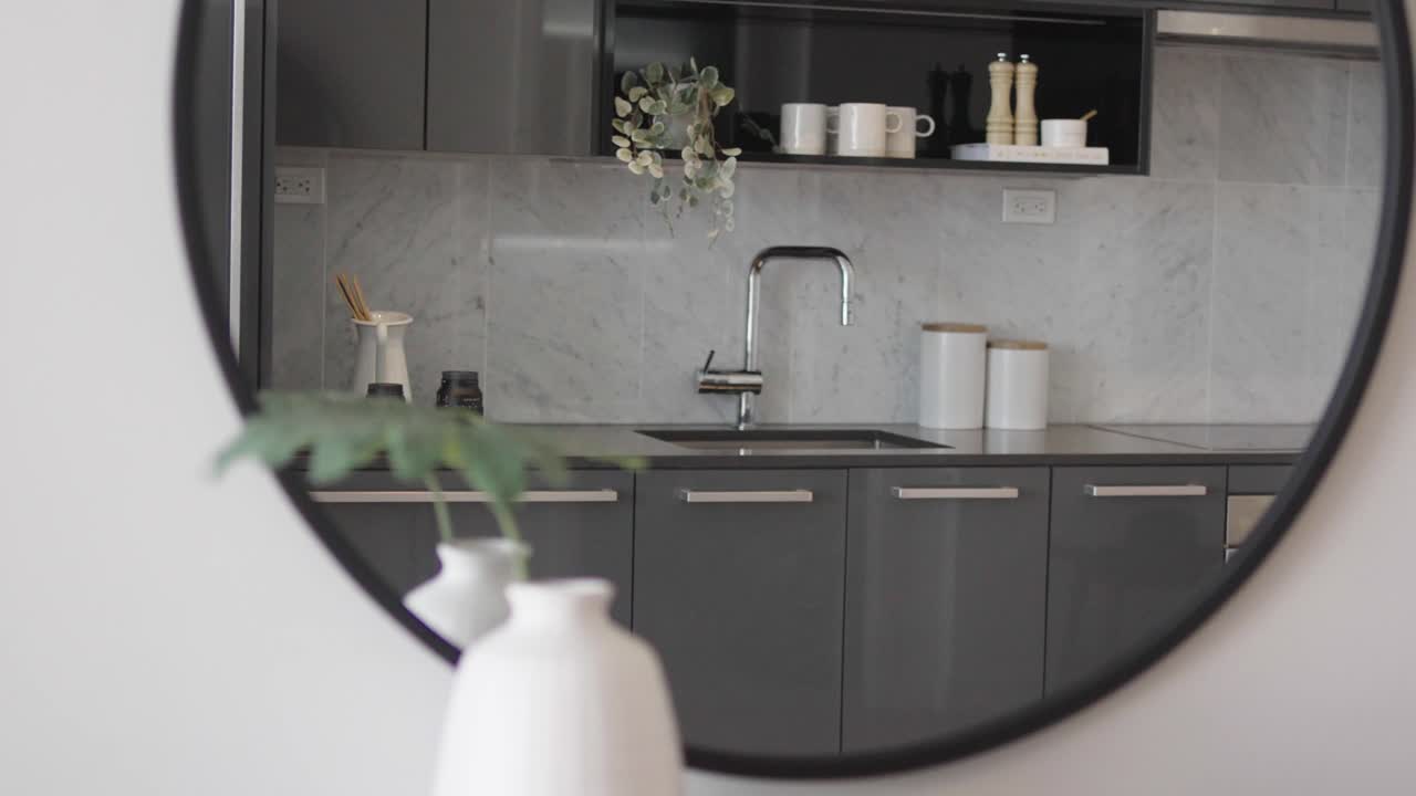 Close up shot of the mirror but focus on the reflection which showing the kitchen area of a high ceiling penthouse condominium unit during a sunny day