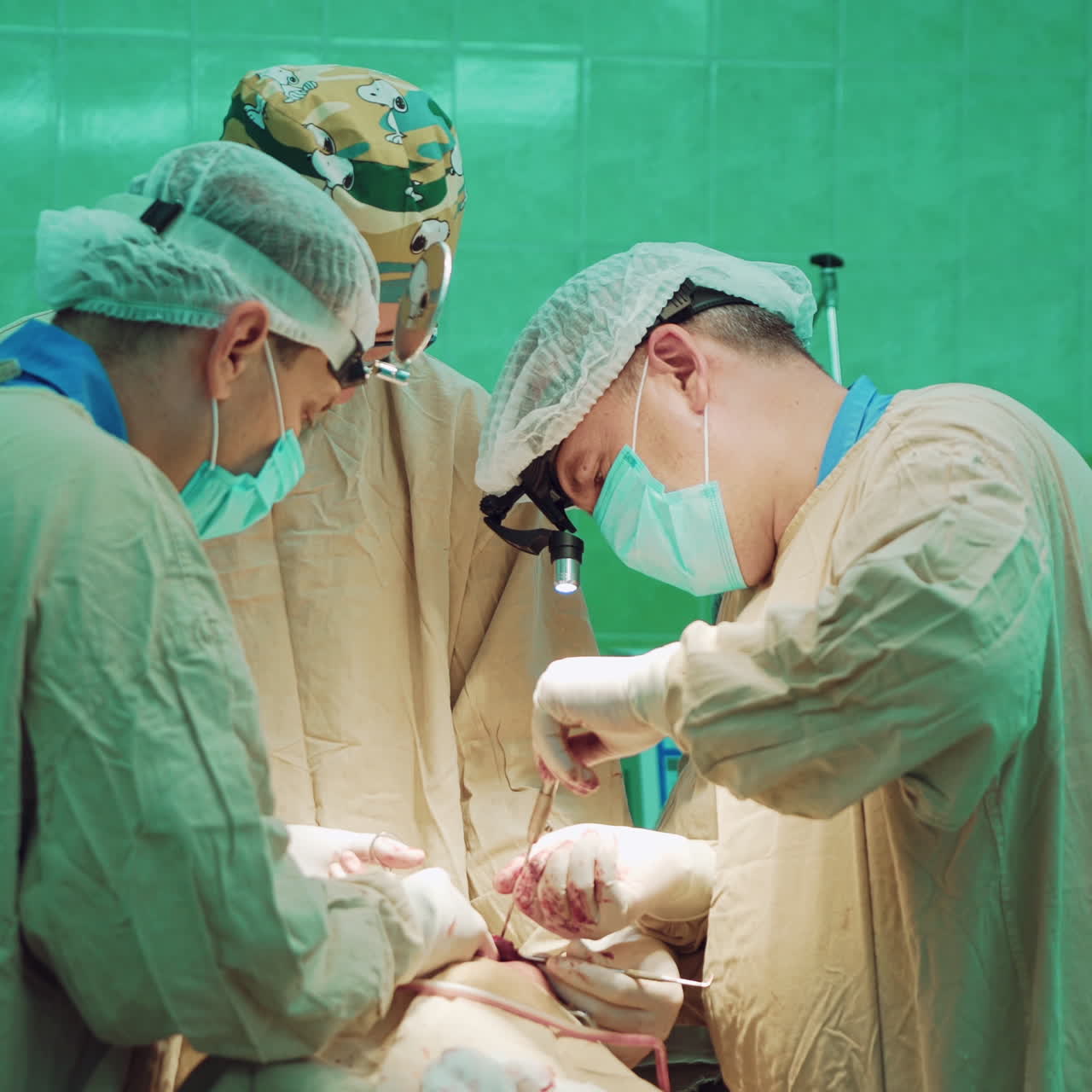 Surgeon takes sterile instrument and does the operation with the help of two specialists. Team of professional surgeons performing surgery on a patient in the hospital operating room. Doctors use medical equipment indoors.