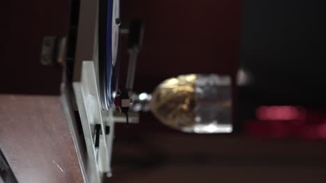 4k vertical, comenzando la reproducción de la grabación de vinilo, colocando la aguja en el disco con un vaso de vino blanco en el fondo