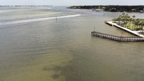 Luftaufnahme-Des-Bootes,-Das-Aus-Dem-Einlass-In-Südflorida-Herausfährt,-Hölzerner-Pier-Im-Vordergrund