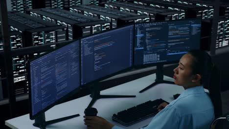 side view of asian woman developer drinking coffee and using computer to write code with multiple screens in data center