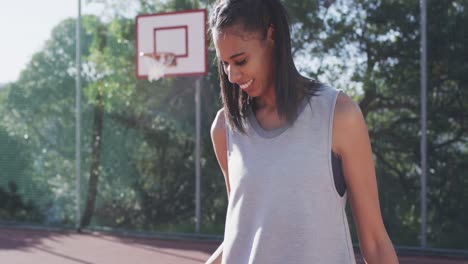 Retrato-De-Una-Jugadora-De-Baloncesto-Afroamericana-Sosteniendo-Una-Pelota-En-Una-Cancha-Soleada,-En-Cámara-Lenta