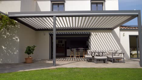 slow establishing shot of furniture sitting under a sun shade in a villa garden