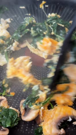 cooking scrambled eggs with spinach and mushrooms