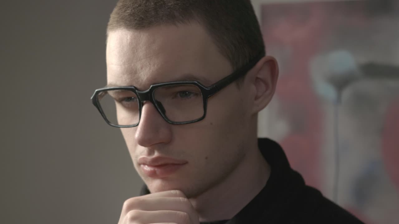 Young Man In Glasses Rubbing His Chin With His Hand.- closeup shot