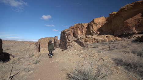 Woman-With-Photo-Camera-Walking-on-Trail-Between-Ruins-of-Pueblo,-Chaco-Culture-National-Historical-Park,-New-Mexico-USA,-Panorama