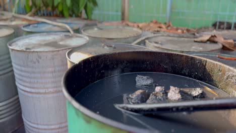 open metal barrel containing dark chemical waste liquid