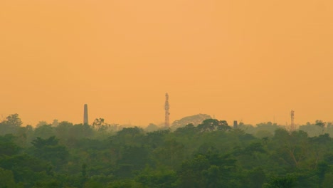 Chimenea-Industrial-Y-Torre-De-Red-De-Transmisores-Sobre-Un-Denso-Bosque.