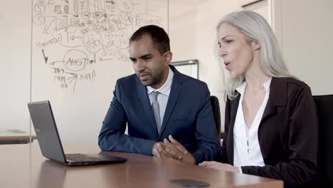 Male-and-female-business-colleagues-waving-hello-at-laptop