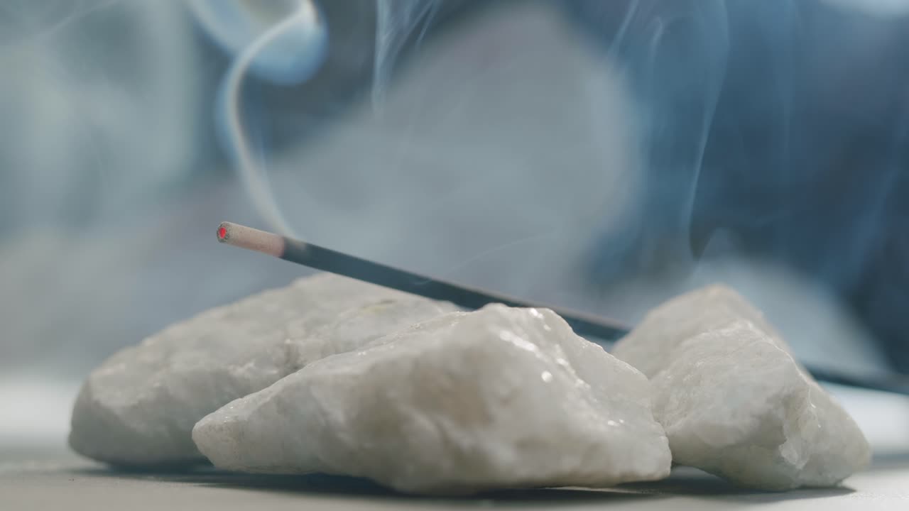 Person holding Palo Santo wood stick in hand, aromatic Palo Santo burning on black background, smoke spreading around, slow motion video clip, high quality 4k close up footage. High quality 4k footage