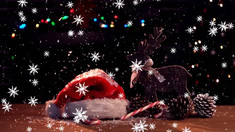 Animation-of-snow-falling-over-santa-hat-and-reindeer-christmas-decoration