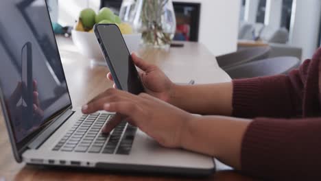 Close-up-of-african-american-plus-size-woman-using-laptop-and-smartphone,-slow-motion