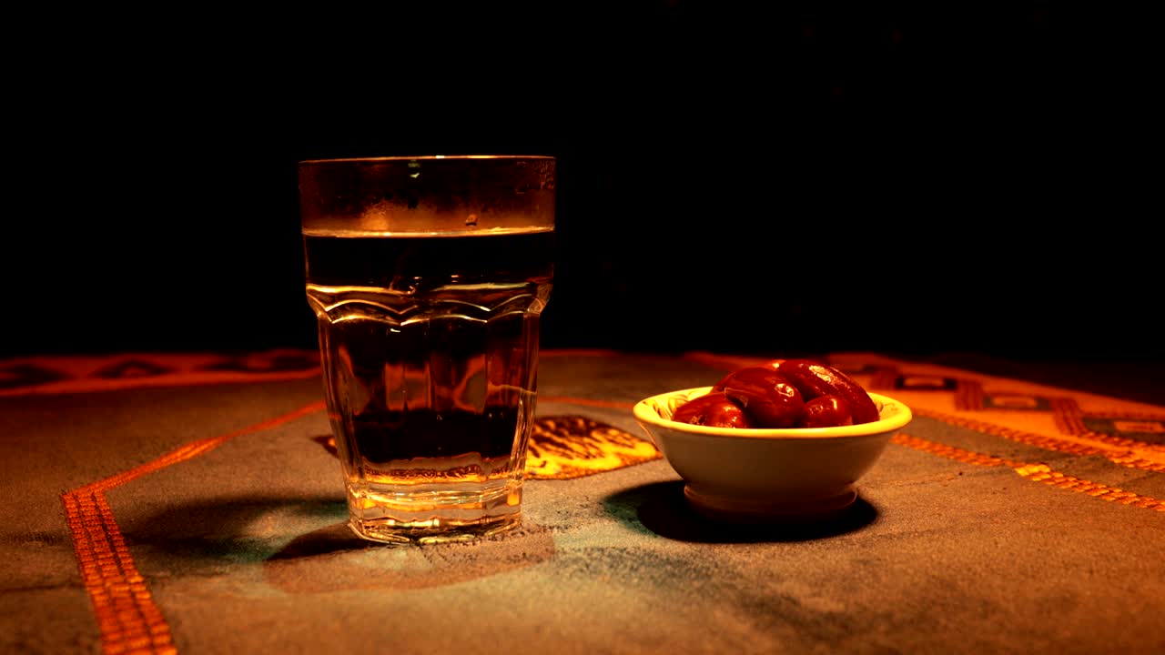agua y dátiles. el iftar es la comida de la noche. vista deslizante de la decoración vacaciones de ramadán kareem. tarjeta de felicitación festiva, invitación para el mes sagrado musulmán ramadán kareem. fondo oscuro. enfoque selectivo
