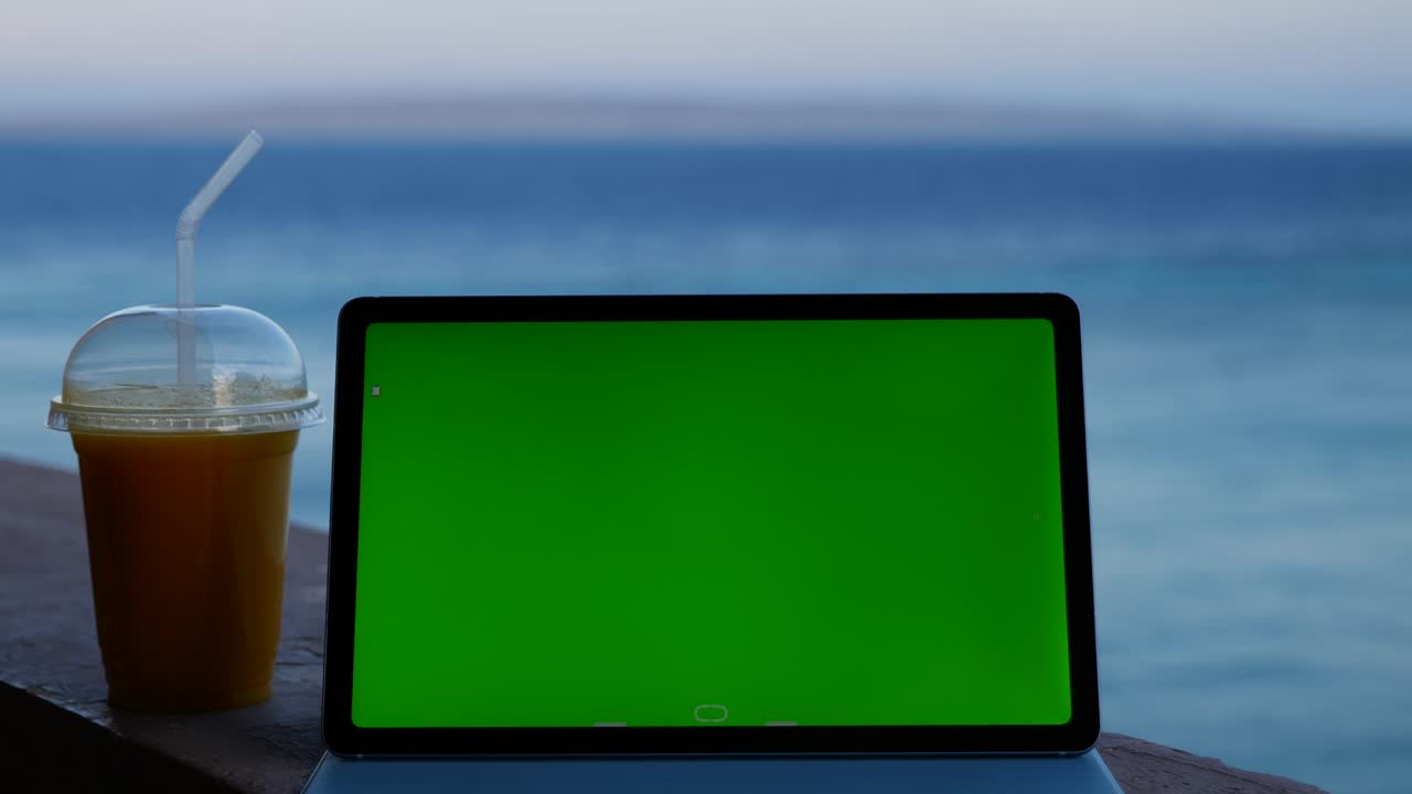 Tablet con schermo verde sul balcone con vista sul mare