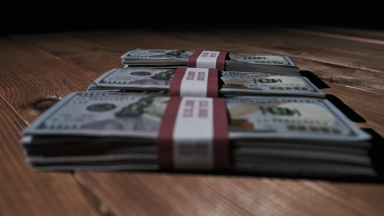 Three Stacks of 10000 American Dollars Banknotes in Bundles Lie on Wooden Table