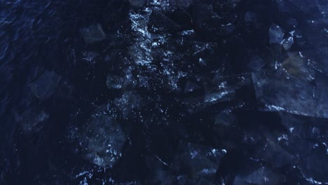 large ice blocks floating in dark deep water, aerial downwards view