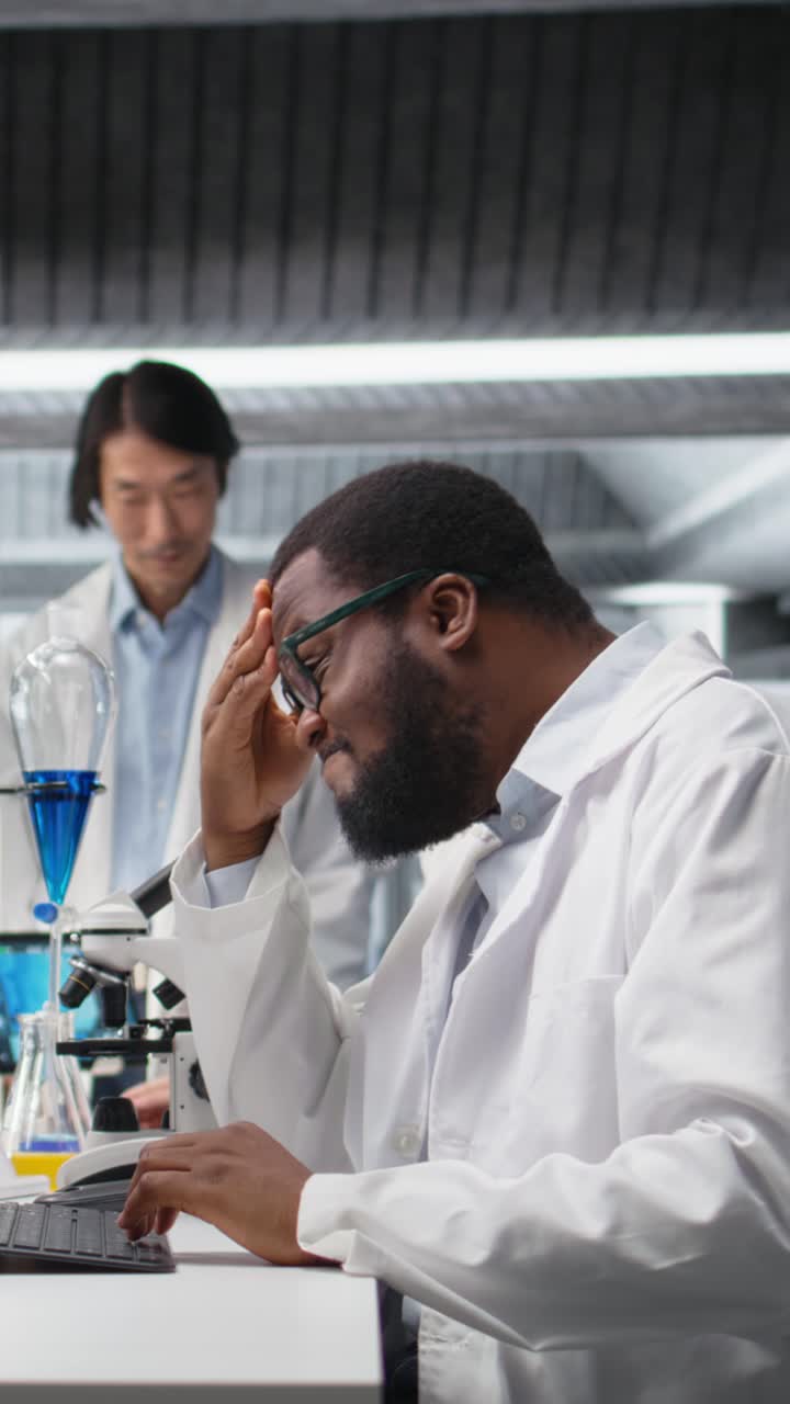 Vertical video Laboratory scientist squinting eyes at computer monitor, thinking